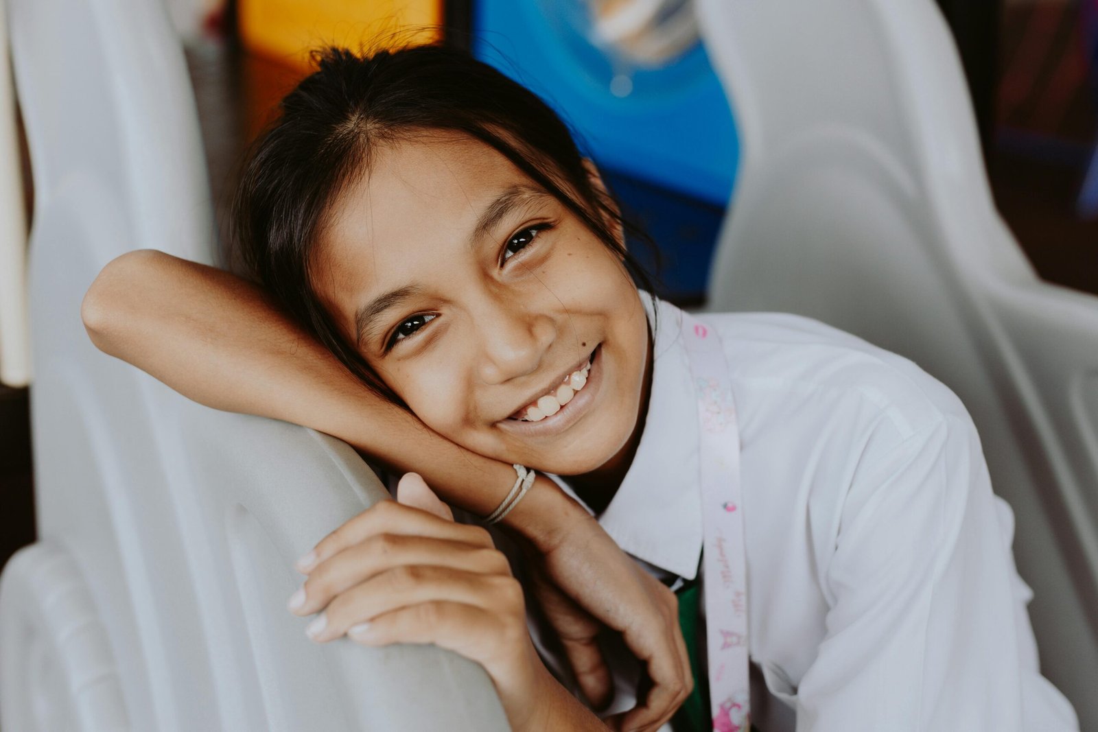 A happy girl student smiling indoors, showcasing youthful joy and relaxation.